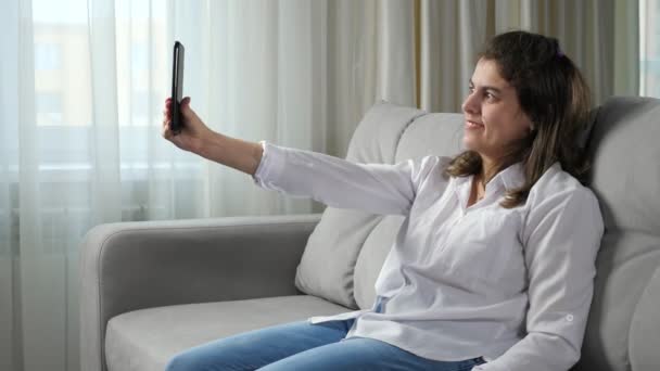 Niepełnosprawna kobieta robi selfie przez telefon na kanapie w domu — Wideo stockowe