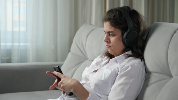 Mujer discapacitada en auriculares escucha música sosteniendo el teléfono — Vídeos de Stock