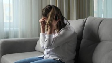 Engelli kadın evdeki kanepede otururken baş ağrısı çekiyor.