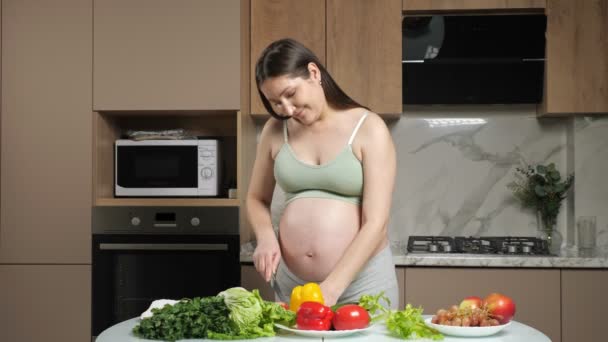 Kobieta w ciąży uderza brzucha cięcia i jedzenia papryki — Wideo stockowe