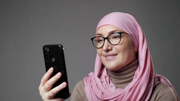 Ung Muselman kvinna i hijab leenden titta på show med telefon — Stockfoto