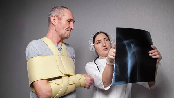 Ortopedista muestra fotografía de rayos X al paciente con vendaje — Foto de Stock