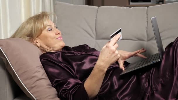 Жінка середнього віку платить за покупки онлайн через ноутбук — стокове відео