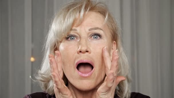 Mujer anciana comprueba las arrugas en la cara mirando con atención — Vídeos de Stock
