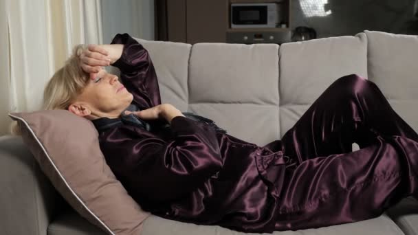 Mujer mayor yace enferma en pijama y bufanda tosiendo — Vídeo de stock