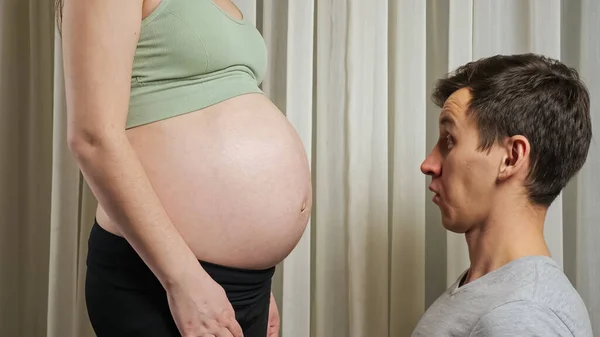 Young father surprised with baby moving in pregnant belly — Stock Photo, Image