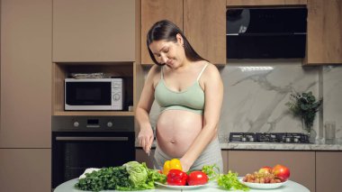 Hamile kadın karnını okşar, biber keser ve yer.