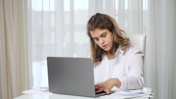 Женщина-инвалид фрилансер работает на ноутбуке из дома за столом — стоковое видео