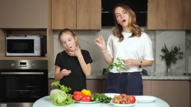 Anne genç kızına mutfakta maydanoz tatması için verir.