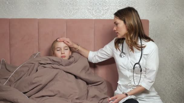 Доктор торкається лоба дівчини-підлітка, що перевіряє температуру — стокове відео