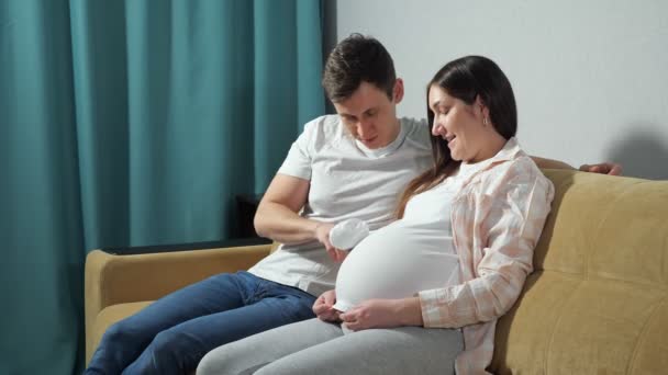 Far leker med barnet på mammas mage med bröst på handen — Stockvideo