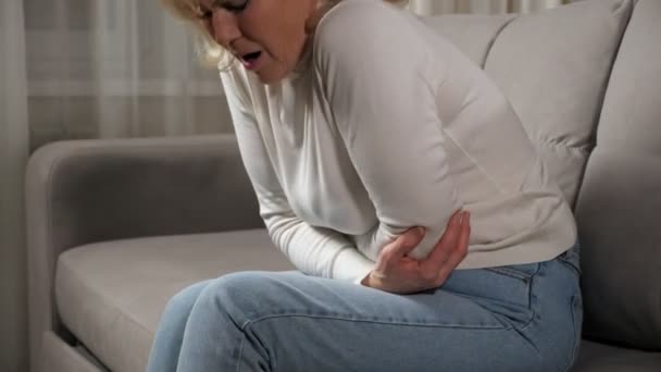 Kvinnan känner svår smärta i lederna på armbågarna sitter på soffan — Stockvideo