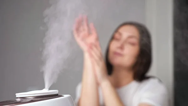 Mujer joven aplica crema en los brazos disfrutando del aire hidratado — Foto de Stock