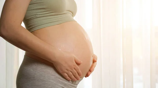 Жінка застосовує протирання зволожуючих кремів на вагітному животі — стокове фото