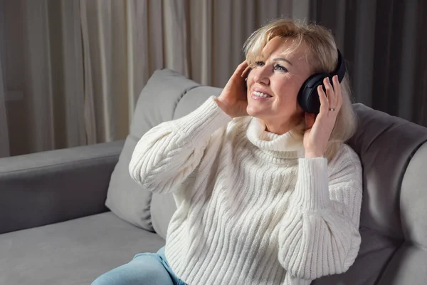 Mujer rubia de mediana edad escucha música a través de auriculares — Foto de Stock