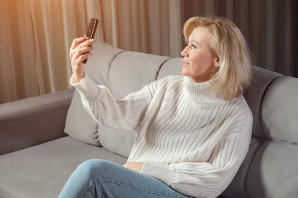 Mature woman communicates via videocall using smartphone — Stock Photo, Image