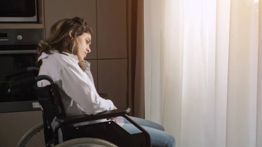 Düşünceli engelli kadın tekerlekli sandalyede oturuyor.