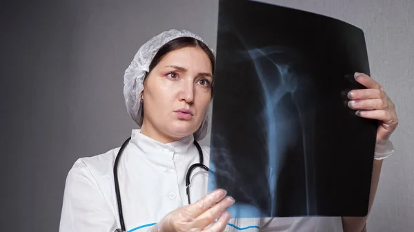 Mujer ortopedista mira la imagen de rayos X en la clínica — Foto de Stock