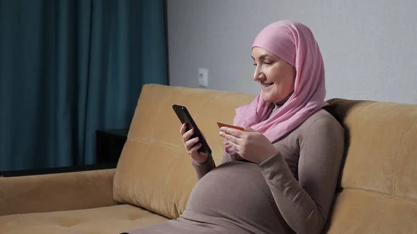 Pregnant woman in hijab checks number and makes phone call — Stockfoto