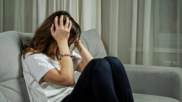 Η καταθλιπτική γυναίκα χειρίζεται το άγχος καθισμένη στον καναπέ στο σπίτι — Φωτογραφία Αρχείου
