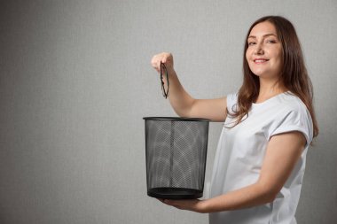 Genç bir kadın çöp kutusuna bardak atıyor.