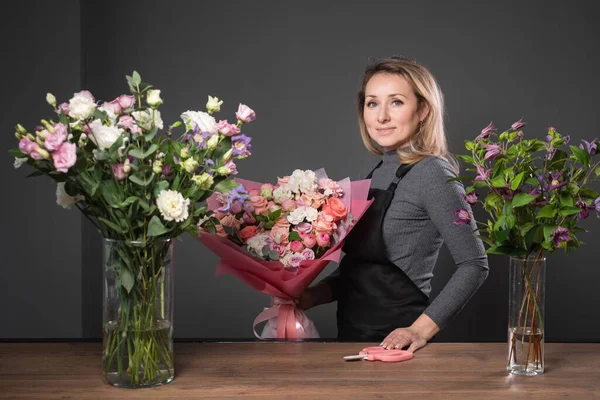 Orgulhoso florista loira mulher detém composto buquê de flores Fotografia De Stock