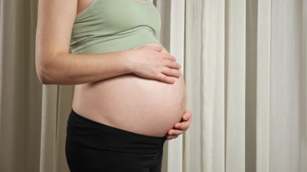Jonge vrouw in sportkleding raakt zwangere buik strelen — Stockvideo