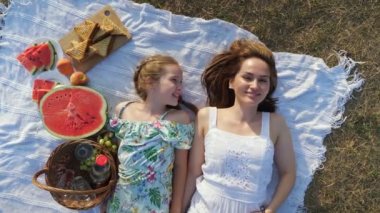 Mutlu anne piknik battaniyesinde yatan kızının burnuna dokunur.