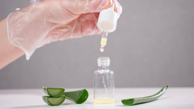 Uzman beyaz masada cam şişeye aloe suyu döker.