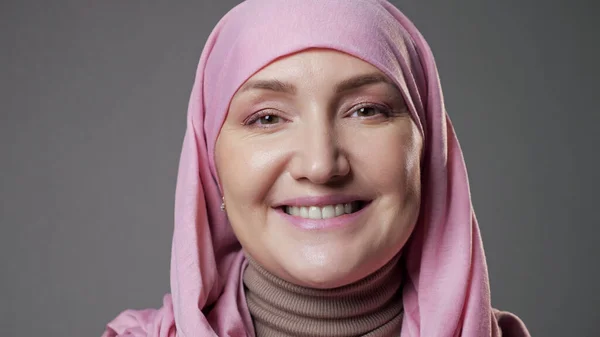 Woman wearing hijab smiles widely looking into camera