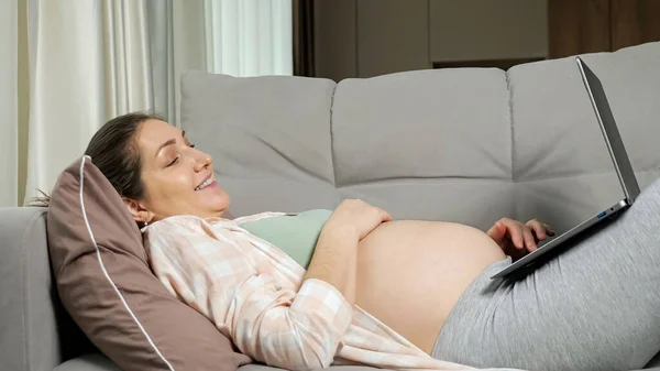 임산부는 온라인으로 아기를 위한 쇼핑을 하고 소파에 누워 있습니다 — 스톡 사진