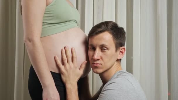 Mann streichelt und hört ungeborenes Baby im Bauch seiner Frau — Stockvideo