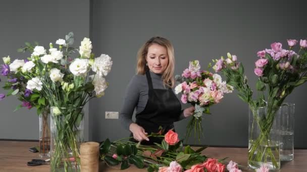 Florist takes pink rose to make elegant bouquet in workshop — Stock Video