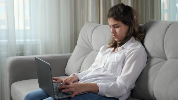 Mulher com deficiência trabalha no computador sentado no sofá em casa — Vídeo de Stock