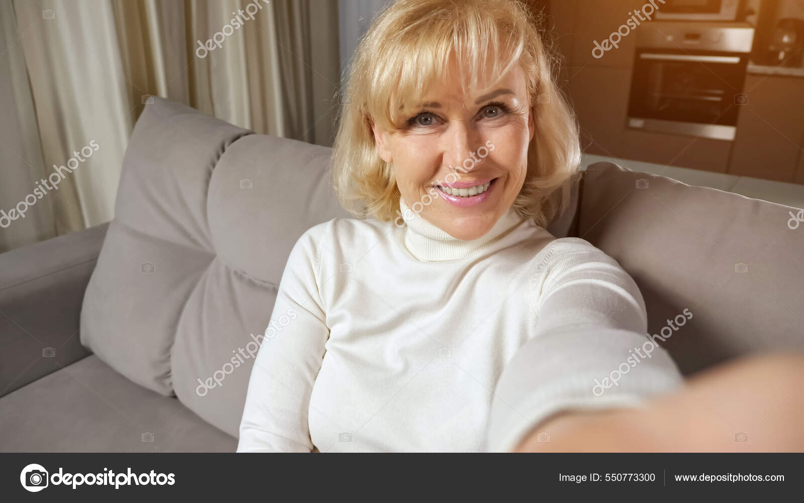 Mature woman with blonde hair takes selfies and smiles Stock Photo by