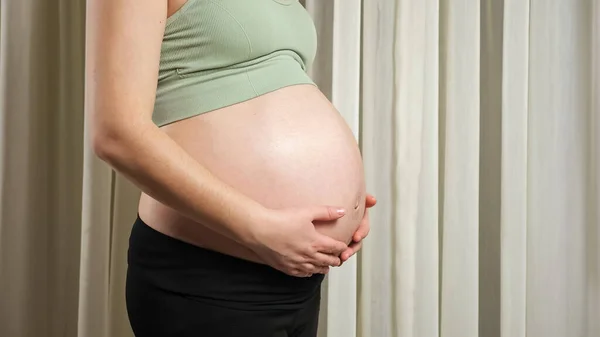 Jonge vrouw in sportkleding raakt zwangere buik strelen — Stockfoto