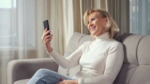 Mature woman communicates via videocall using smartphone — Stock Photo, Image