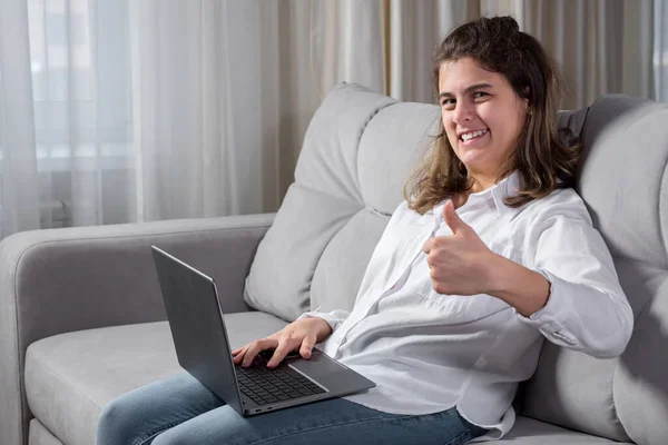 Mulher com deficiência trabalha no computador sentado no sofá em casa — Fotografia de Stock