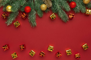 Noel kompozisyonu. Kırmızı arkaplanda kozalaklı dallar ve dekoratif süsler..