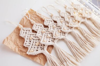 Noel makromu dekoru. El işi kağıdında Noel ağaçları ve beyaz arka plan. Doğal malzemeler, pamuk ipliği, tahta boncuklar. Eko dekorasyonlar, süsler, el yapımı dekorasyon. Kış ve Yeni Yıl tatilleri.