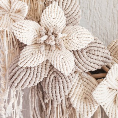 Beyaz dekoratif duvarda büyük bir pamuk çiçekli Macrame çelengi. Doğal pamuk iplik ve ip. Ev için eko dekor. Yaratıcı bir insan için yaratıcı tebrik kartı. Kapat.