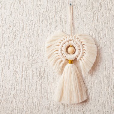 Noel makromu dekoru. Beyaz alçı duvarlı arka planda Noel meleği. Doğal malzemeler, pamuk ipliği, tahta boncuklar. Eko dekorasyonlar, süsler, el yapımı dekorasyon. Kapatın. Boşluğu kopyala