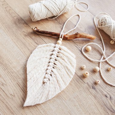Doğal renklerde Macrame yaprağı ve ahşap bir masada uzanan iplik sargıları. Odanı daha rahat ve benzersiz yapmak için pamuk ip makrome. Kadın hobisi. El yapımı duvar asma dekoru. Boşluğu kopyala