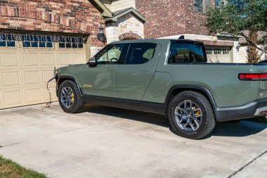 Rivian elektrik kamyonu evin önünde şarj oluyor.