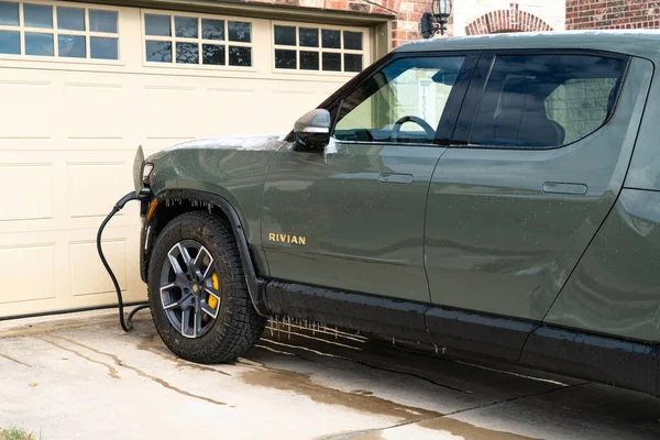 Rivian elektrik kamyonunun evin önünde şarj olurken yakın plan görüntüsü.