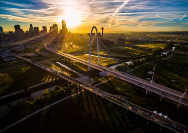 Aerial drone view of Dallas , Texas skyline cityscape high above skyscrapers and modern suspension bridge over trinity river park with amazing sunrise in background of downtown