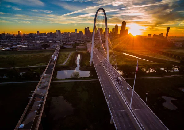 Aerial drone view of Dallas , Texas skyline cityscape high above skyscrapers and modern suspension bridge over trinity river park with amazing sunrise in background of downtown