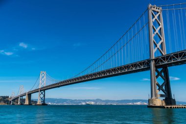 Oakland 'dan San Francisco Körfez Köprüsü' ne kadar olan uzun altyapı planı güneşli bir öğleden sonra Kaliforniya, San Francisco sahilinde büyük bir asma köprü ile Bay Area 'yı geçiyor.