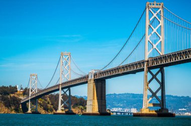 Oakland 'dan San Francisco Körfez Köprüsü' ne kadar olan uzun altyapı planı güneşli bir öğleden sonra Kaliforniya, San Francisco sahilinde büyük bir asma köprü ile Bay Area 'yı geçiyor.