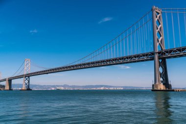 Oakland 'dan San Francisco Körfez Köprüsü' ne kadar olan uzun altyapı planı güneşli bir öğleden sonra Kaliforniya, San Francisco sahilinde büyük bir asma köprü ile Bay Area 'yı geçiyor.